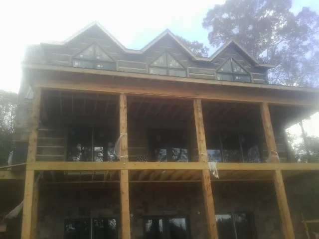 Dormers and porch framing on a large log home under construction — Roof Coating work by our crew in Port Republic